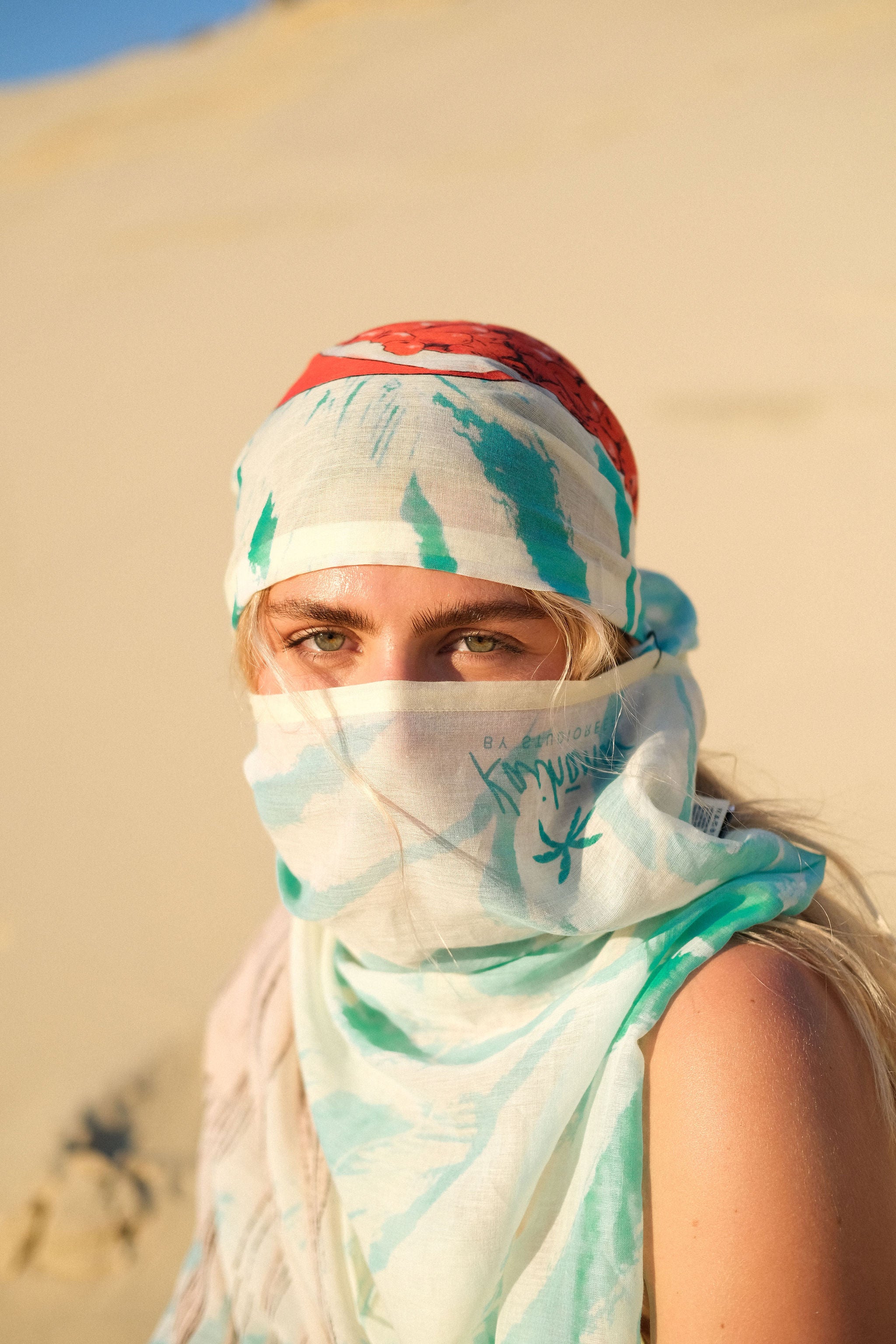 Femme portant le paréo Palma Granada turquoise dans les dunes au coucher du soleil